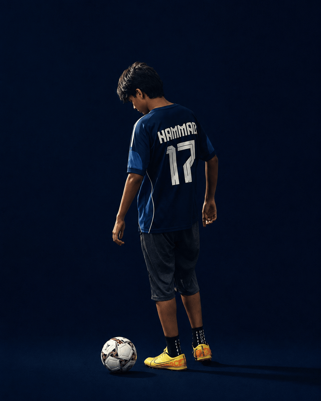 A U16 TWA FC player on a navy ground with the ball at his feet